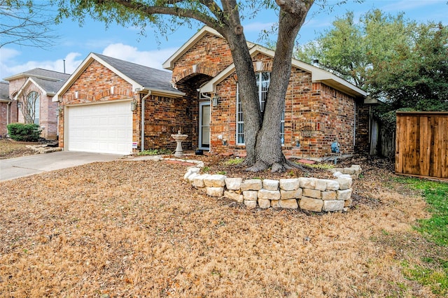 view of front of home featuring driveway, brick siding, an attached garage, and fence