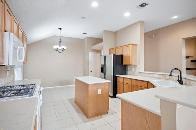 kitchen featuring a center island, visible vents, a sink, white appliances, and a peninsula