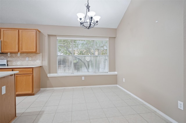 kitchen with lofted ceiling, a chandelier, baseboards, light countertops, and backsplash