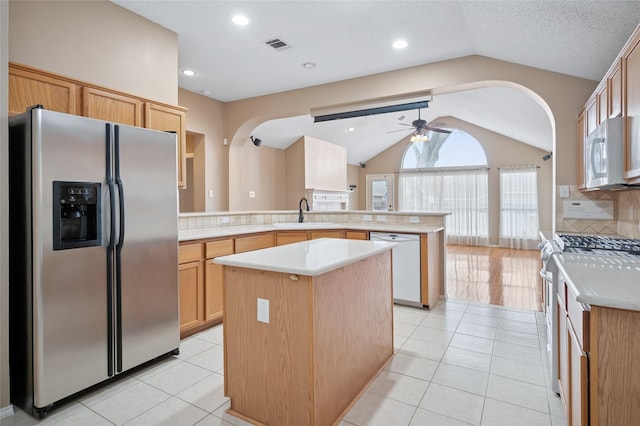 kitchen featuring a peninsula, white appliances, lofted ceiling, and light tile patterned flooring