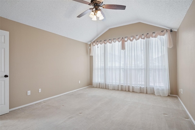 carpeted empty room featuring a ceiling fan, vaulted ceiling, a textured ceiling, and baseboards