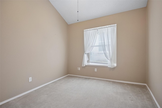 carpeted spare room with lofted ceiling and baseboards