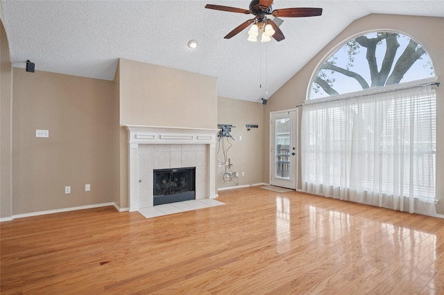 unfurnished living room featuring baseboards, ceiling fan, wood finished floors, a textured ceiling, and a fireplace