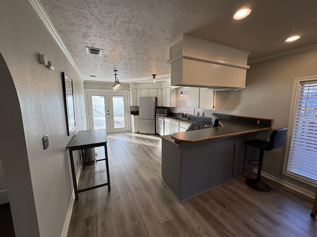 kitchen featuring dark countertops, visible vents, appliances with stainless steel finishes, white cabinetry, and a sink