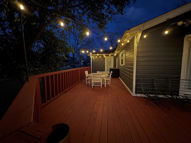 deck at night featuring outdoor dining space