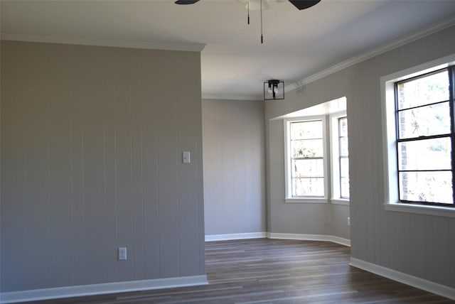 empty room with dark wood-style floors, crown molding, baseboards, and a ceiling fan