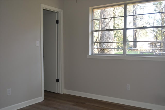 unfurnished room featuring dark wood-style floors and baseboards