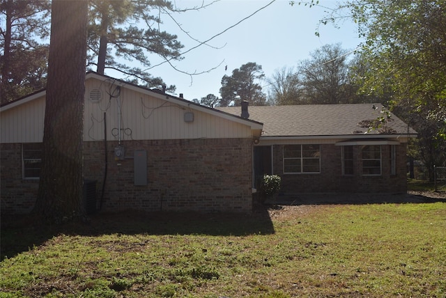 rear view of property featuring a lawn and brick siding