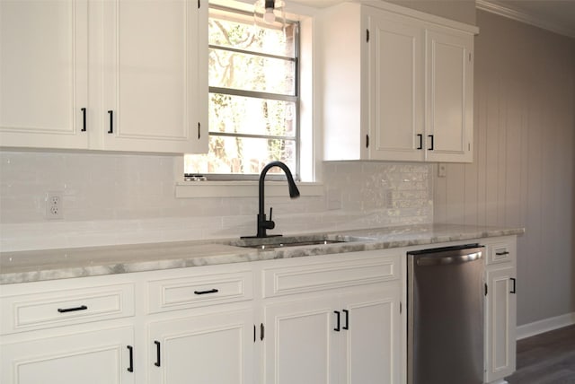 kitchen featuring stainless steel dishwasher, backsplash, a sink, and white cabinets