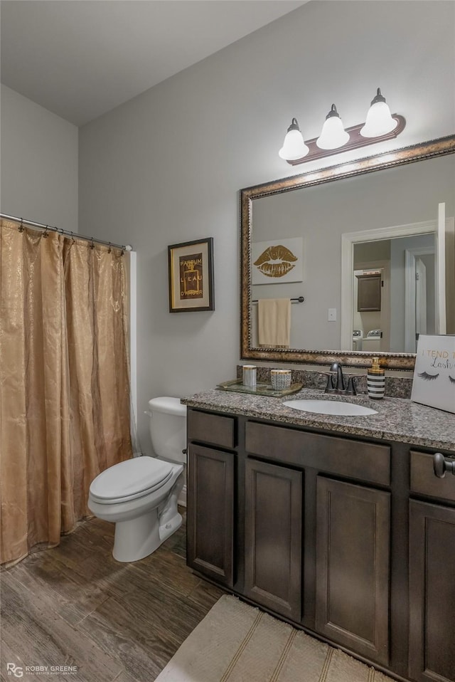 full bath with a shower with curtain, toilet, wood finished floors, and vanity