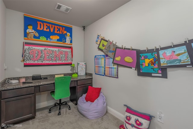 carpeted office space featuring visible vents, baseboards, and built in study area