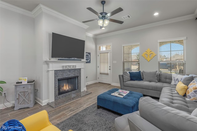 living room with wood finish floors, visible vents, a fireplace, crown molding, and baseboards