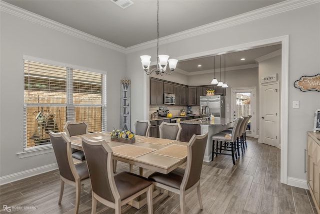 dining room featuring crown molding, visible vents, baseboards, and wood tiled floor