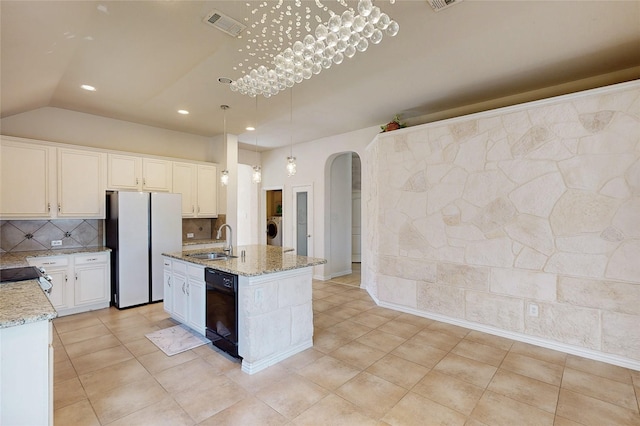 kitchen with washer / dryer, arched walkways, dishwasher, freestanding refrigerator, and a sink