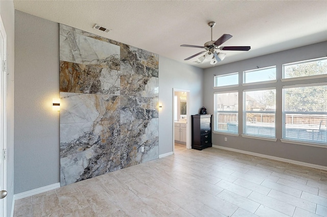 spare room featuring baseboards, ceiling fan, visible vents, and a textured ceiling