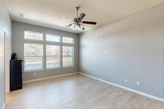 empty room featuring ceiling fan, visible vents, and baseboards