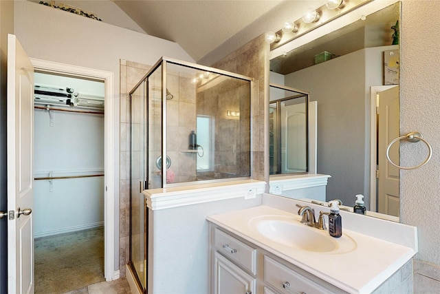 bathroom with lofted ceiling, a shower stall, a walk in closet, and vanity