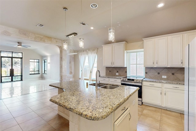 kitchen featuring visible vents, open floor plan, a sink, stainless steel range with electric cooktop, and a wealth of natural light