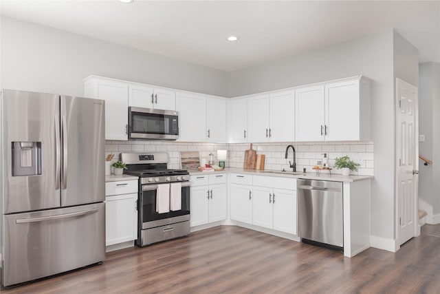 kitchen featuring appliances with stainless steel finishes, dark wood finished floors, light countertops, and a sink