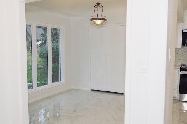 unfurnished dining area with marble finish floor and baseboards