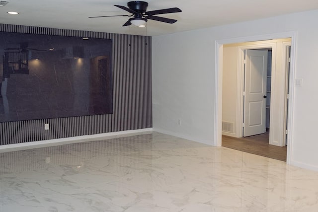 unfurnished room with ceiling fan, marble finish floor, visible vents, and baseboards