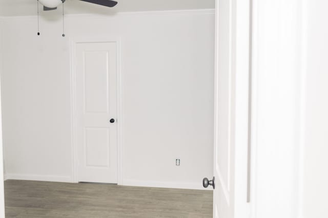 interior space with baseboards, wood finished floors, a ceiling fan, and crown molding