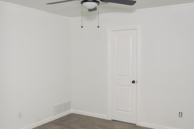 empty room featuring dark wood-style floors, visible vents, ornamental molding, and baseboards