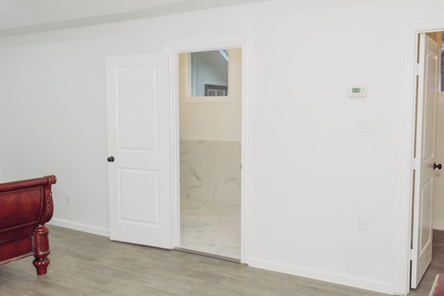 bedroom featuring ensuite bathroom, wood finished floors, and baseboards