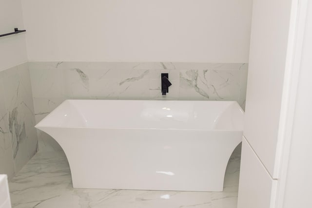 full bathroom featuring a freestanding bath and marble finish floor