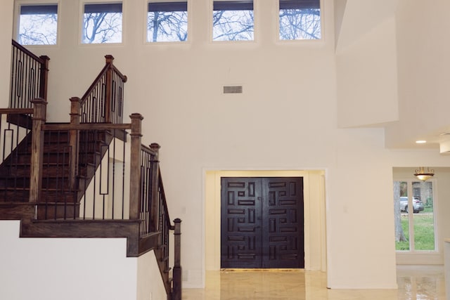 entrance foyer featuring stairs, a high ceiling, and visible vents