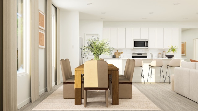 dining space featuring baseboards and light wood-style floors