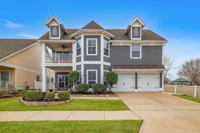 view of front facade with a balcony, a garage, a shingled roof, fence, and concrete driveway