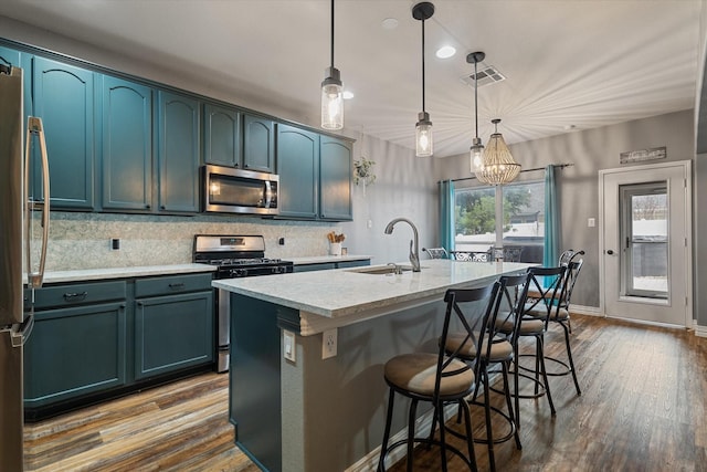 kitchen with dark wood-style floors, a breakfast bar, a center island with sink, appliances with stainless steel finishes, and a sink