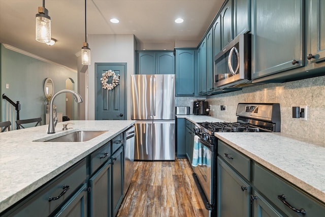 kitchen with pendant lighting, dark wood finished floors, light countertops, appliances with stainless steel finishes, and a sink