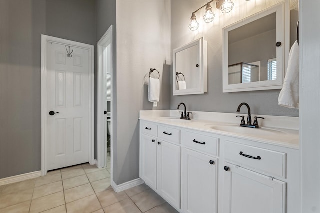 bathroom with double vanity, a sink, baseboards, and tile patterned floors