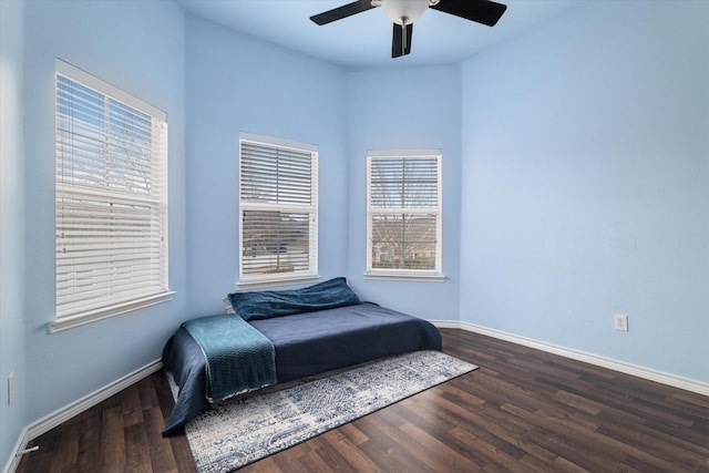 bedroom with dark wood-type flooring, a ceiling fan, and baseboards