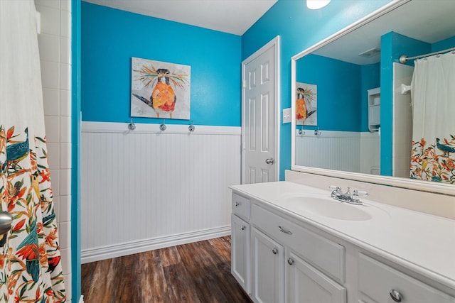 bathroom with a wainscoted wall, a shower with shower curtain, wood finished floors, visible vents, and vanity