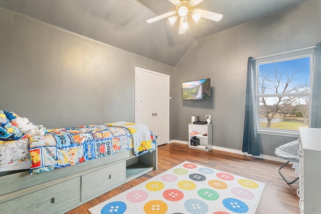 bedroom featuring lofted ceiling, a closet, ceiling fan, wood finished floors, and baseboards