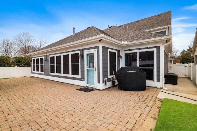 back of property with a patio area, a fenced backyard, and roof with shingles