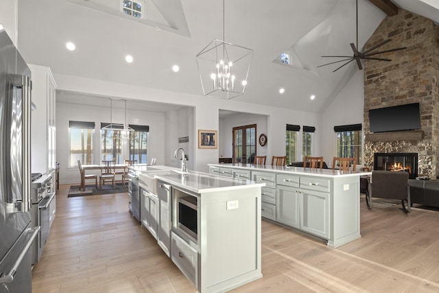 kitchen with appliances with stainless steel finishes, light wood-style floors, a fireplace, and a large island