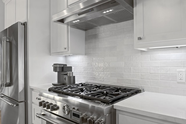 kitchen with tasteful backsplash, white cabinets, high end appliances, wall chimney exhaust hood, and light countertops