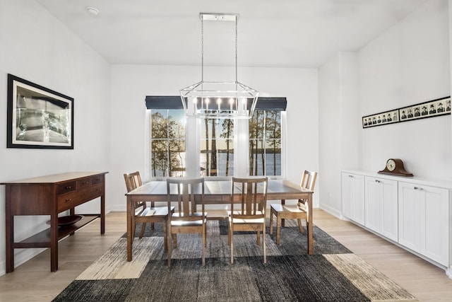 dining area featuring light wood finished floors, baseboards, and a notable chandelier