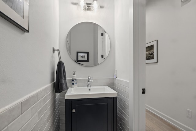 bathroom featuring a wainscoted wall, wood finished floors, vanity, and tile walls