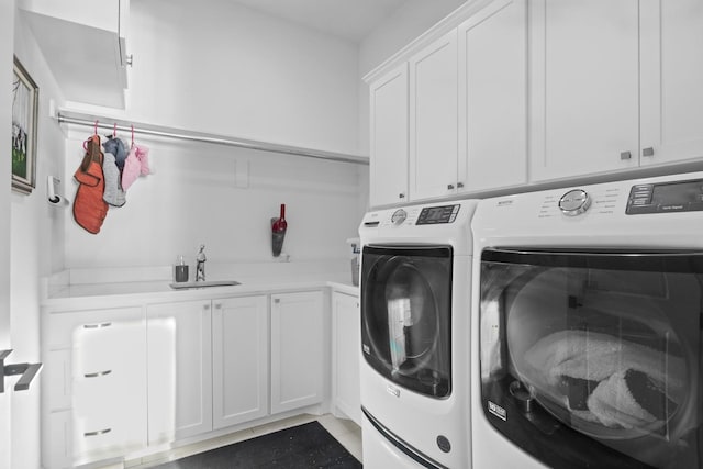 washroom featuring washing machine and dryer, a sink, and cabinet space