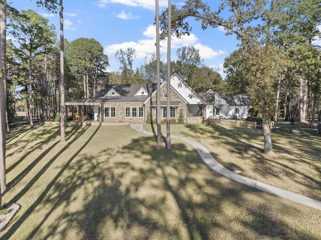 view of front of property featuring stone siding, a chimney, and a front yard