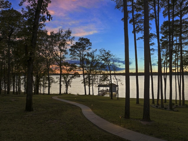 view of property's community with a yard, a dock, and a water view