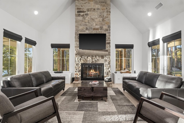 living area featuring plenty of natural light, a fireplace, high vaulted ceiling, and wood finished floors