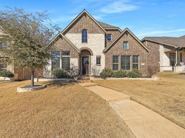 view of front of home with stone siding, brick siding, and a front lawn