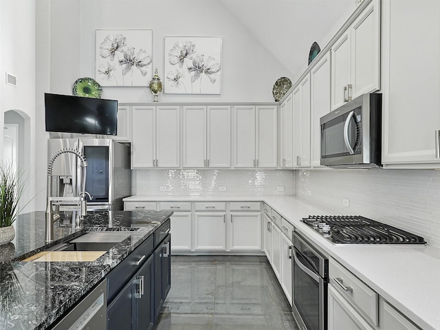 kitchen with arched walkways, marble finish floor, tasteful backsplash, appliances with stainless steel finishes, and white cabinetry