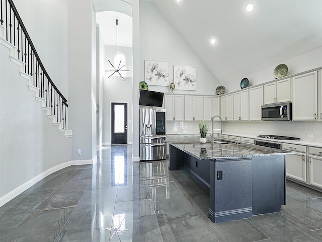 kitchen featuring a towering ceiling, marble finish floor, stainless steel appliances, stone counters, and a sink